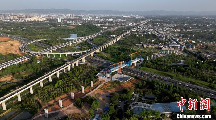 航拍正在建設(shè)的跨越成都繞城高速公路連續(xù)梁施工現(xiàn)場，旁邊依次為已運營的成渝高速鐵路和機(jī)場高速公路?！⒅铱?攝