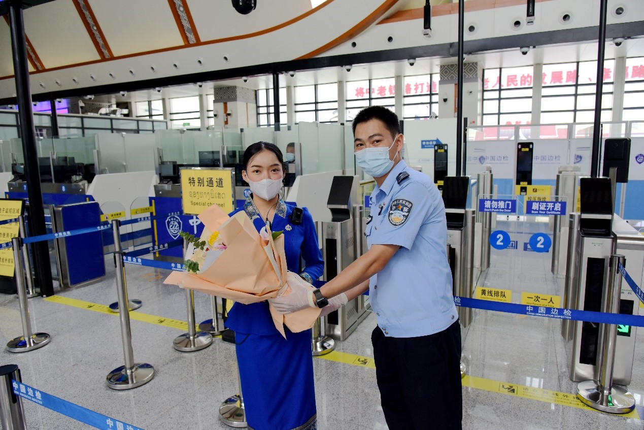 磨憨出入境邊防檢查站民警為中老鐵路第100萬名出入境旅客，D888次國際旅客列車老撾籍乘務員森達拉·妮緹婭（Sengdala Nitiya），送上鮮花。黃遠飛 攝