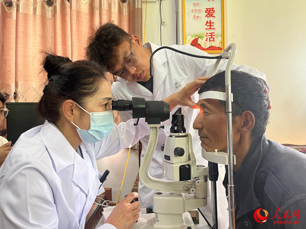 王紅英（左）和團隊成員為達熱村村民檢查眼睛。人民網(wǎng)記者 杜燕飛攝
