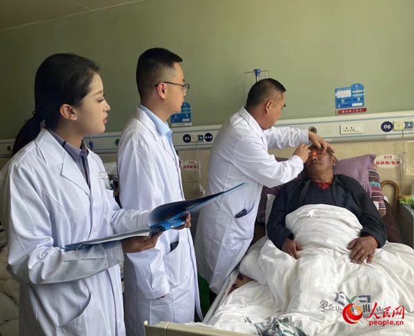 董光明（左三）帶領(lǐng)醫(yī)生對患者進行術(shù)前檢查。人民網(wǎng)記者 杜燕飛攝