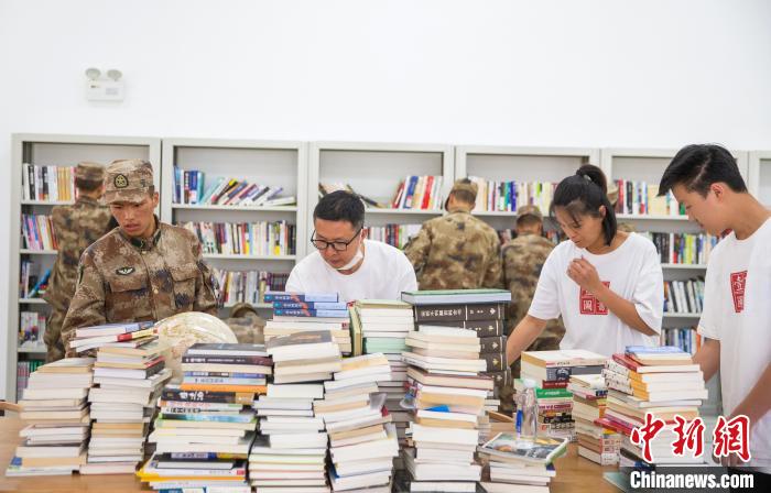 圖為志愿者們和邊防戰(zhàn)士整理圖書?！詵| 攝
