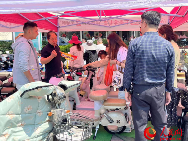 某電動自行車品牌工作人員向消費(fèi)者介紹以舊換新相關(guān)情況。人民網(wǎng)記者 杜燕飛攝