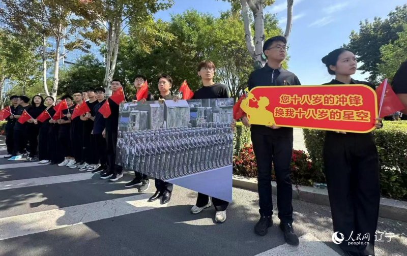 沈陽市人民廣場上，大學生們手持閱兵的圖片，告慰英烈。人民網(wǎng)記者 周頌雪攝