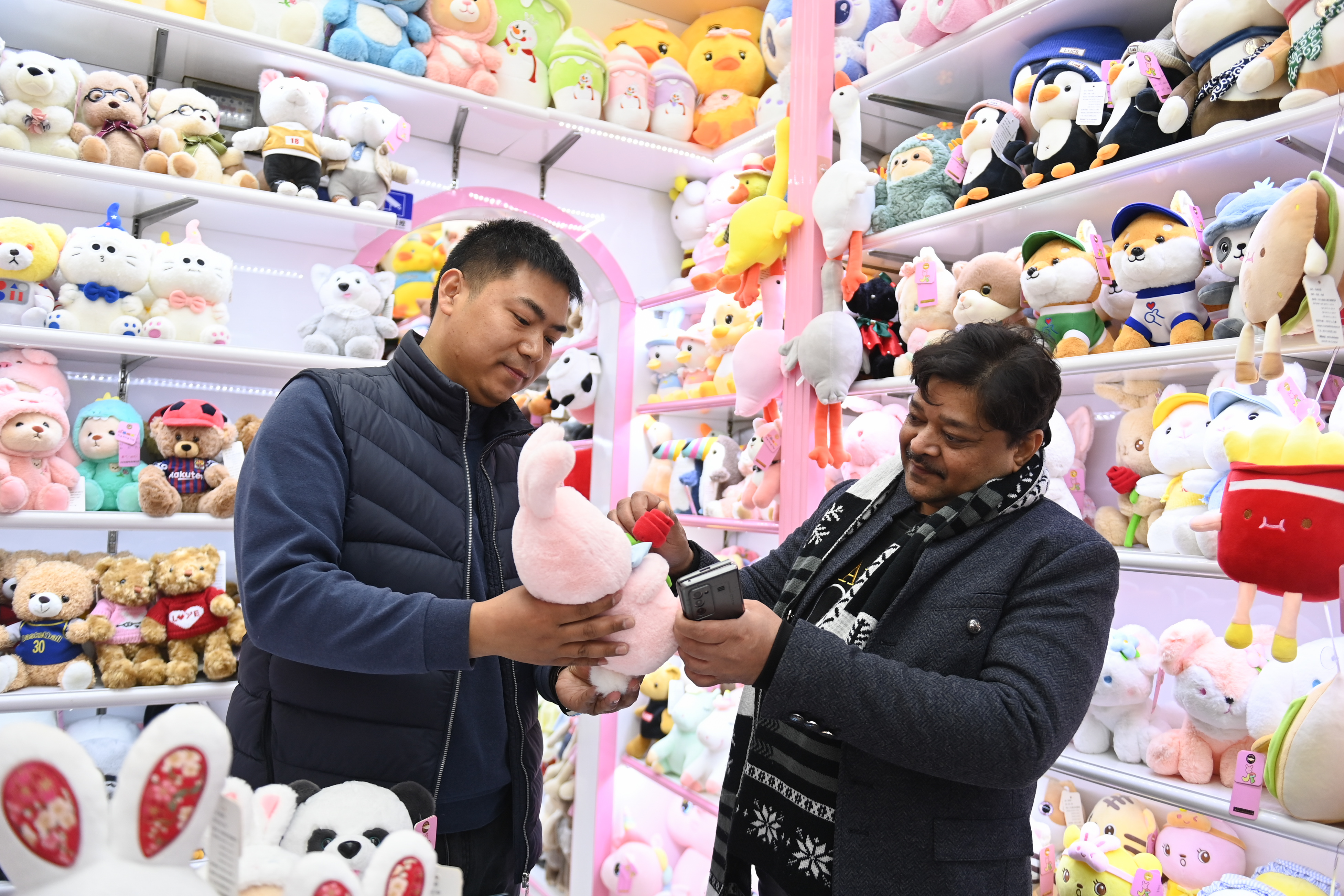 2023年2月2日，來自印度的客商（右）在義烏國(guó)際商貿(mào)城的一家玩具店鋪內(nèi)選購。