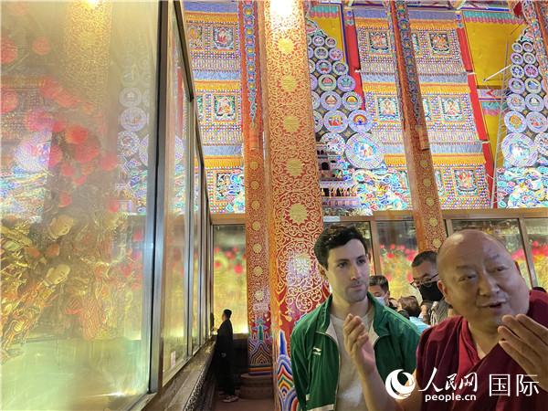7月25日，省級非物質(zhì)文化遺產(chǎn)項目塔爾寺酥油花的代表性傳承人朋措堅參（右）在塔爾寺酥油花館講解酥油花的制作過程。人民網(wǎng) 謝瑩攝