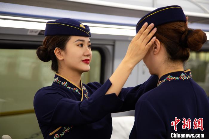 圖為青藏鐵路西格段“復(fù)興號”動車組乘務(wù)員互相整理新制服。　李磊 攝