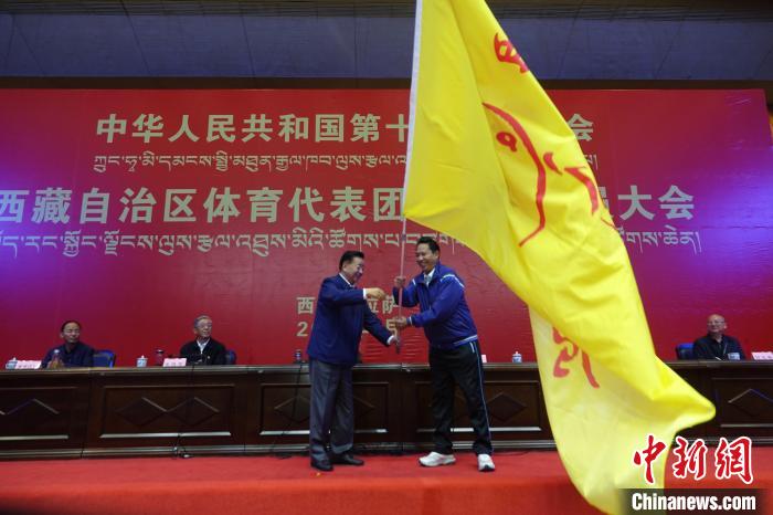 西藏自治區(qū)副主席甲熱·洛桑丹增授代表團團旗，西藏自治區(qū)體育局局長尼瑪次仁接旗。　冉文娟 攝