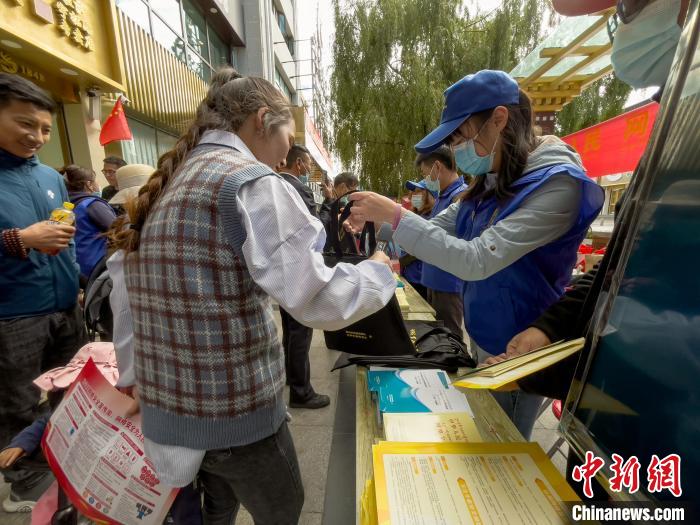 圖為志愿者為市民發(fā)放網(wǎng)絡安全宣傳手冊。　謝牧 攝