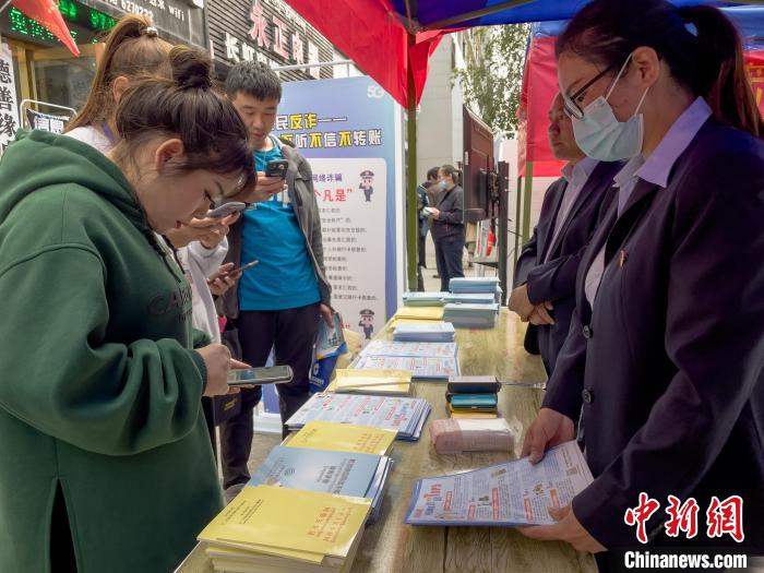 圖為工作人員正在向路過市民介紹國家反詐中心軟件的功能?！≈x牧 攝