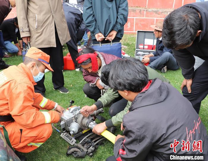 圖為森林消防員為護(hù)林員講解滅火裝備的使用方法?！〔际猩窒乐ш?duì) 供圖