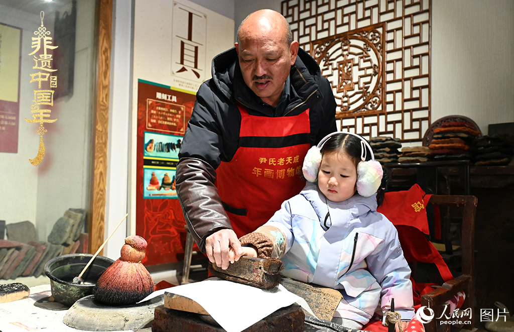 2025年1月27日，河南開封朱仙鎮(zhèn)木版年畫藝人尹國法指導(dǎo)小朋友研習(xí)年畫印制技藝。朱仙鎮(zhèn)木版年畫源自漢唐壁畫藝術(shù)，是中國木版年畫的鼻祖。2006年5月20日，朱仙鎮(zhèn)木版年畫經(jīng)國務(wù)院批準(zhǔn)列入第一批國家級非物質(zhì)文化遺產(chǎn)名錄。人民網(wǎng)記者 王玉興攝